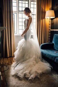 Dramatic Bridal Portrait of bride standing in window