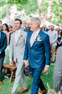Groom looks at his partner as they approach the altar