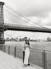 A timeless black and white portrait of a couple embracing by the water, capturing a genuine connection during a multi-day wedding celebration.