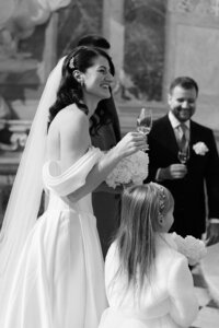 Authentic moment of a bride laughing with a glass of champagne after her ceremony at the beautiful Valtice Castle.