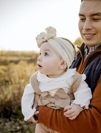 A little girl is being held by her dad with baeutiful golden light in the background