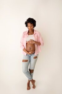 Brandy gazing down at belly during timeless studio maternity session