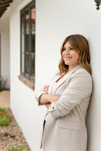 Female entrepreneur leaning against a Spanish-style building during a Ventura County personal brand photography session by photographer Jaclyn Hernandez.
