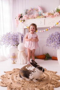 Toddler stands near a live bunny during Easter Mini Session at Holy City Babies Portrait Studio in Charleston, SC.