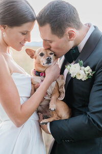 The bride and groom kiss their puppy