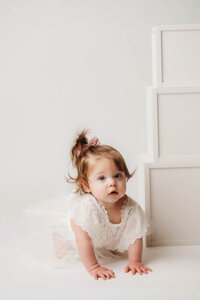Charleston Cake Smash Photographer- Baby looks into the camera during Milestone Portraits at Holy City Babies Portrait Studio in Charleston, SC.