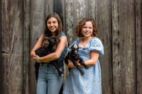 Teen sisters holding baby goats during family photography session in Eastern North Carolina