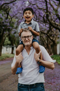 A dad and son photographed in front of an avenue of Jacarandas in Rosebank, Johannesburg.