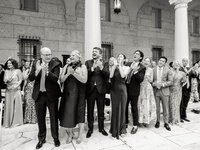 Guests rise and applaud during the ceremony in the Boston Public Library courtyard, columns and arched windows behind them.