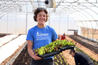 FarmerHoldingOrganicGreensInGreenhouseAtStoneBankFarmMarket