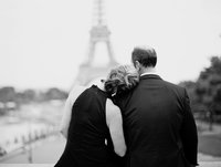 wife lays head on husband's shoulder in front of Eiffel Tower