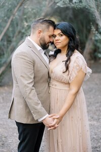 Dilorio family parents holding hands and sharing an intimate moment in a tree-lined Las Vegas setting, captured during a romantic outdoor couples portrait session.