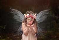 Jacksonville, FL portrait session capturing a Little fairy in Palatka, closing her eyes and gently releasing shimmering fairy dust from her cupped hands during a signature fairy adventure session with Nature's Child Photography.