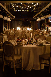 Breathtaking luxury wedding reception setup with hanging chandeliers and white roses in a grand ballroom.