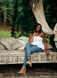 Senior portrait at Bella Sera Gardens in Loxley, Alabama — sitting on a large wooden swing,
holding her hair.