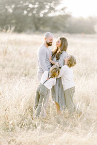 A family photo of a Frisco family posing in an open grassy field.