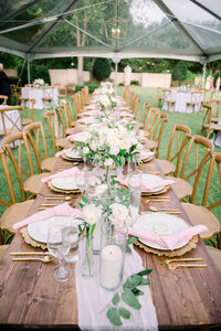 medium shot of wooden wedding table with pink and gold table placements