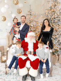 family dressed in beautiful christmas attire smiles with boston santa claus
