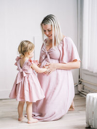 Pregnant mom is kneeling while her toddler daughter is touching her bump in a studio maternity session in Seattle