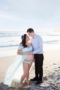 glowing expecting couple during candid moment on the beach near the Santa Monica Pier maternity session