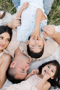 boy laughing and family smiling at him in outdoor family photos in peoria il