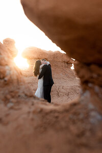 bride and groom kissing in goblin valley under sunset