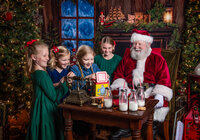 Children gathered around Santa reacting to a surprise jack-in-the-box during a Santa’s Magical Christmas photography session in Jacksonville, Florida with Nature’s Child Photography, cozy North Pole decor, vintage toys, and excited holiday laughter filling the scene.