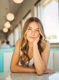 Senior portrait at Sunliner Diner in Gulf Shores, Alabama — close-up in the booth with her elbow
resting on the table.