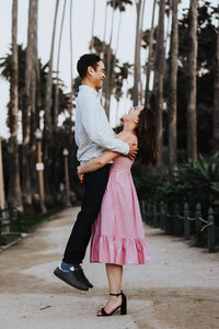 Elopement Photographer, man and woman hug and smile at each other, they stand  within a promenade of palm trees