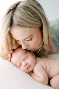 Mom kissing newborn baby during in-home lifestyle session Miami