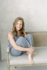 A beautiful photo of a Dallas business woman sitting on a bench at a Dallas photography studio posing for her professional headshots.