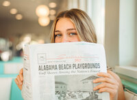Senior portrait at Sunliner Diner in Gulf Shores, Alabama — sitting in a teal booth, peeking over
a newspaper.
