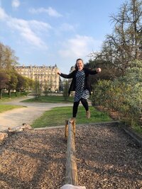 Abigail jumping from a beam at a playground in Paris, France