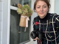 April Budney Founder of Old Whaling Co on her front porch on Johns Island, South Carolina with her camera in her favorite vintage equestrian sweater. 