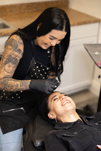 Beauty professional with long dark hair working on client’s brows in salon setting. Photograph by Yucaipa branding photographer Kaitlyn Dawn Photography.
