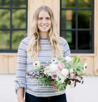 Brit of Homestead Wisconsin, online business coaching client, posing with flowers in front of her barn.