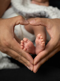 Pasadena newborn photography close up of hands around the newborn’s feet forming a heart shape, captured with soft natural light and true to life color.