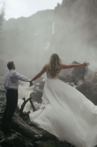 A couple standing at the base of bridal veil falls, Telluride on their wedding day.