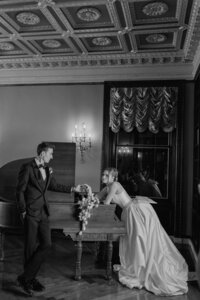 Bride leaning on piano with groom at The War Memorial in Grosse Pointe