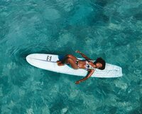 Traveler floating on a paddleboard in turquoise waters, embracing relaxation and adventure.