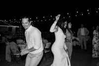 Black-and-white photo of the groom dancing with guests at the wedding reception