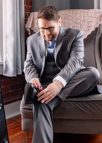 Grooms detail getting ready photo putting on his shoe.