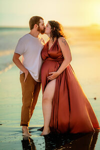 Pregnant couple sharing a kiss during golden hour maternity session in Atlantic Beach North Carolina