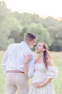 expecting couple laughing during their maternity session in Manassas, Virginia, taken by a Northern VA maternity photographer