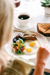 Breakfast plate and coffee photographed over the shoulder at a garden table