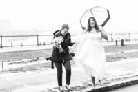 Photographer walking with bride in the rain