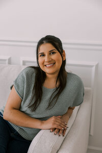 Woman leaning on the arm of a loveseat and smiling
