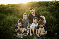 a father sits with his four sons in the summer sunshine