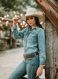 Senior portrait at Triple T Farms in Fruitdale, Alabama — leaning against a wooden post, tipping
her cowboy hat.