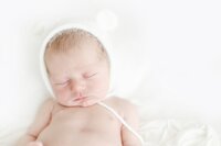 close up of baby in white fuzzy bear hat